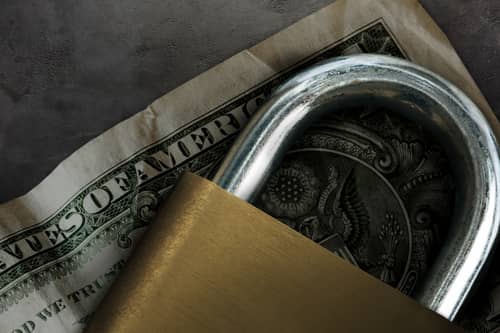 Cadenas sur un billet symbolisant les mesures de sécurité financière ou conservatoires, pouvant accompagner une procédure d’injonction de payer.
