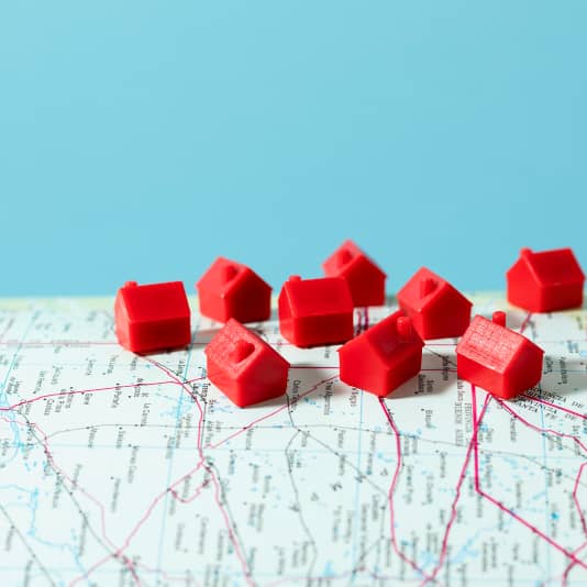 Habitations miniatures rouges sur une carte, symbolisant la gestion de patrimoine immobilier via une SCI à Lille avec l’accompagnement d’un avocat.