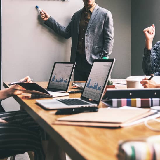 Réunion d’entreprise autour d’un tableau, avec ordinateurs portables et documents de gestion